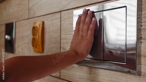 the child presses a button on the wall, flushes the toilet