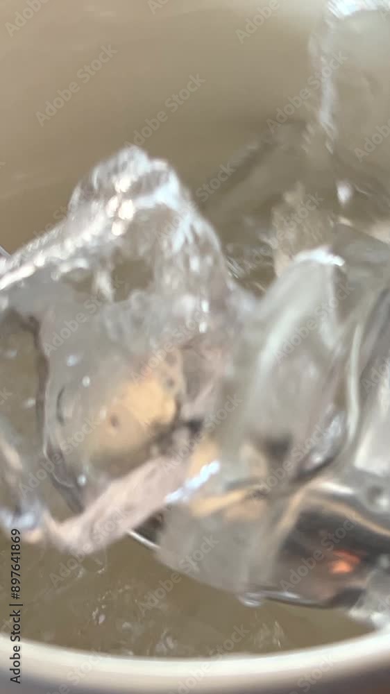 Ice in a cup spoon water glass falling ice cube. slow motion falls ice in cold mineral water. soda water with bubbles on white background. glass water close up. summer drink with ice. fizzy drink. bar Ice in a cup spoon water glass falling ice cube. slow motion falls ice in cold mineral water. soda water with bubbles on white background. glass water close up. summer drink with ice. fizzy drink. bar