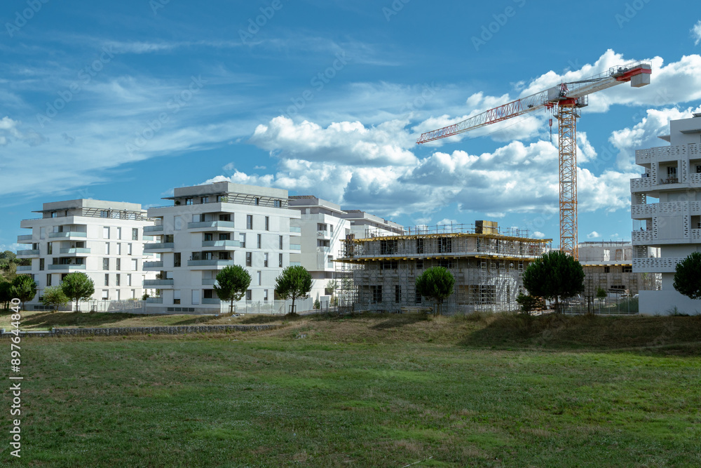 un quartier tout neuf avec des immeubles , dont un en construction avec une grue et des espaces verts un quartier tout neuf avec des immeubles , dont un en construction avec une grue et des espaces verts