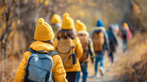 the back view of young children in yellow hat with backpacks traveling together on a school field trip day