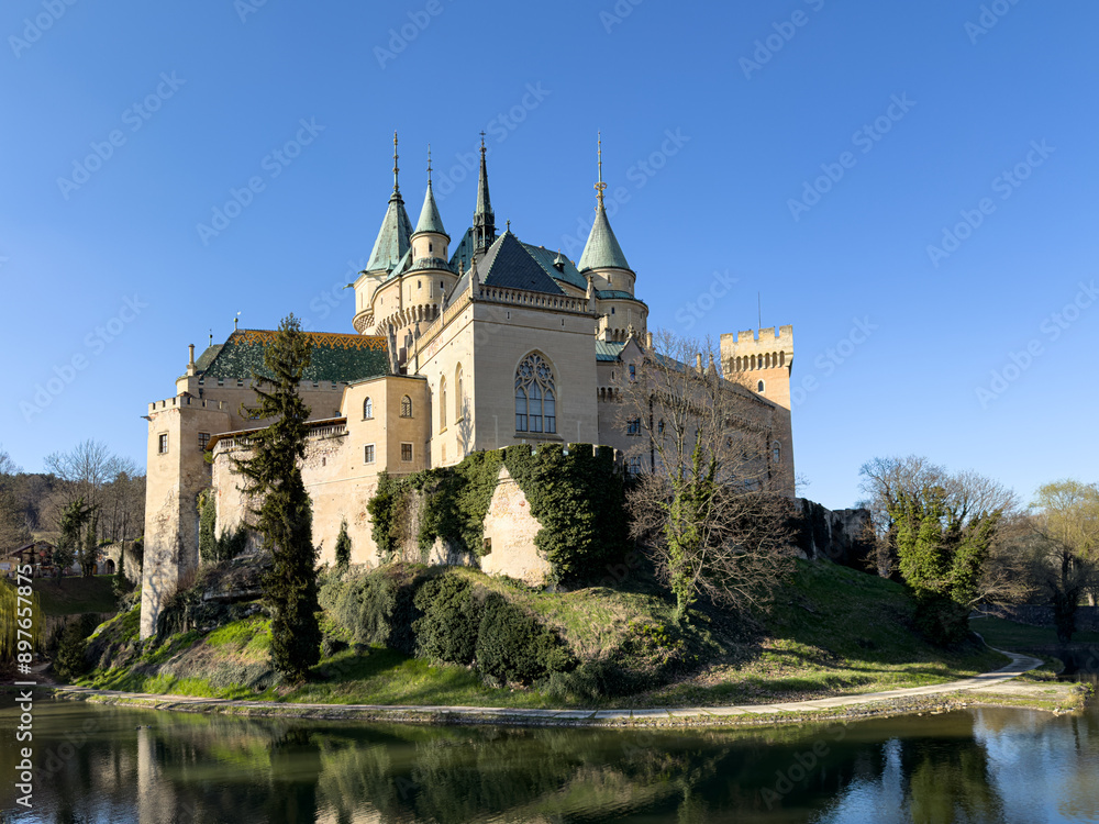 Majestic Bojnice Castle by a riverside, reflecting in the water, showcasing medieval architecture, serene surroundings, and cultural heritage in Slovakia. Majestic Bojnice Castle by a riverside, reflecting in the water, showcasing medieval architecture, serene surroundings, and cultural heritage in Slovakia.
