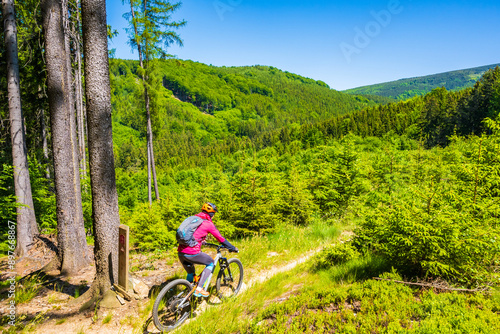 Obraz na płótnie Woman with backpack riding mountain bike on single track trail among green hills in Jizera Mountains, Singletrk pod Smrkem Czech Republic w salonie