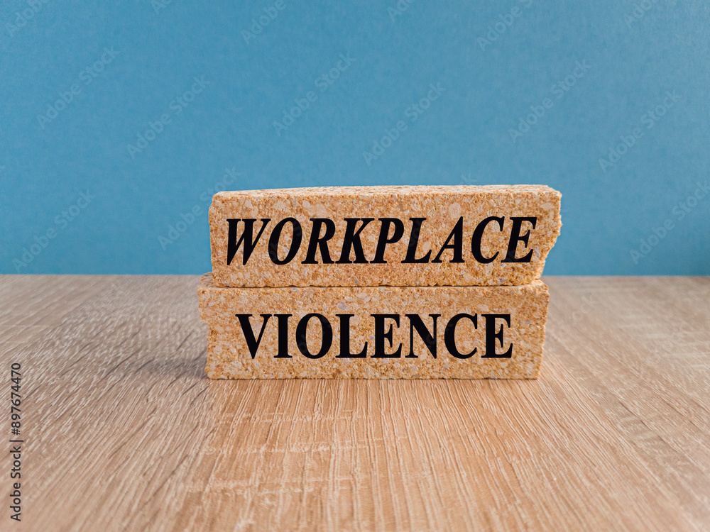 WORKPLACE VIOLENCE symbol. Concept words WORKPLACE VIOLENCE on brick blocks. Beautiful blue background, wooden table. Business concept. Copy space.