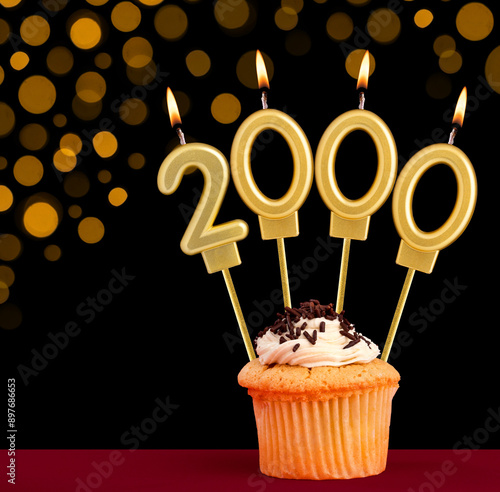 Number 2000 birthday candle - Cupcake on black background with out of focus lights