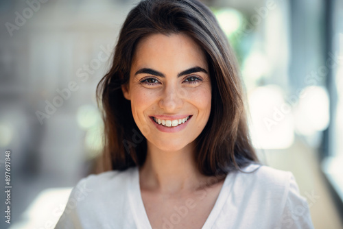 Free Download Portrait of smiling young woman posing while looking at camera in the living room at home. - GFXLoad