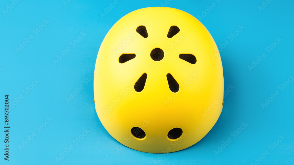 Yellow helmet on blue color background. Child's outdoors activity safety protection: rollers, bicycle, skateboard Yellow helmet on blue color background. Child's outdoors activity safety protection: rollers, bicycle, skateboard