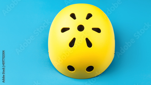 Yellow helmet on blue color background. Child's outdoors activity safety protection: rollers, bicycle, skateboard