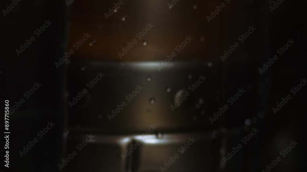 A Close-up of Multiple Plastic bottles on the Manufacturing Facility. Plastic bottles are being slowly filled with the Beverage. Dark Plastic bottles for Industrial Beverage Production. Manufacturing. A Close-up of Multiple Plastic bottles on the Manufacturing Facility. Plastic bottles are being slowly filled with the Beverage. Dark Plastic bottles for Industrial Beverage Production. Manufacturing.