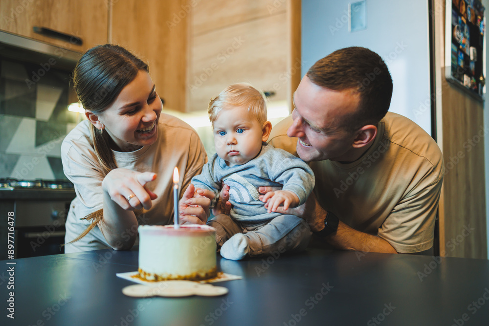 A young couple with a little son in the kitchen with a cake. Parents celebrate their son's birthday. A young couple with a little son in the kitchen with a cake. Parents celebrate their son's birthday.