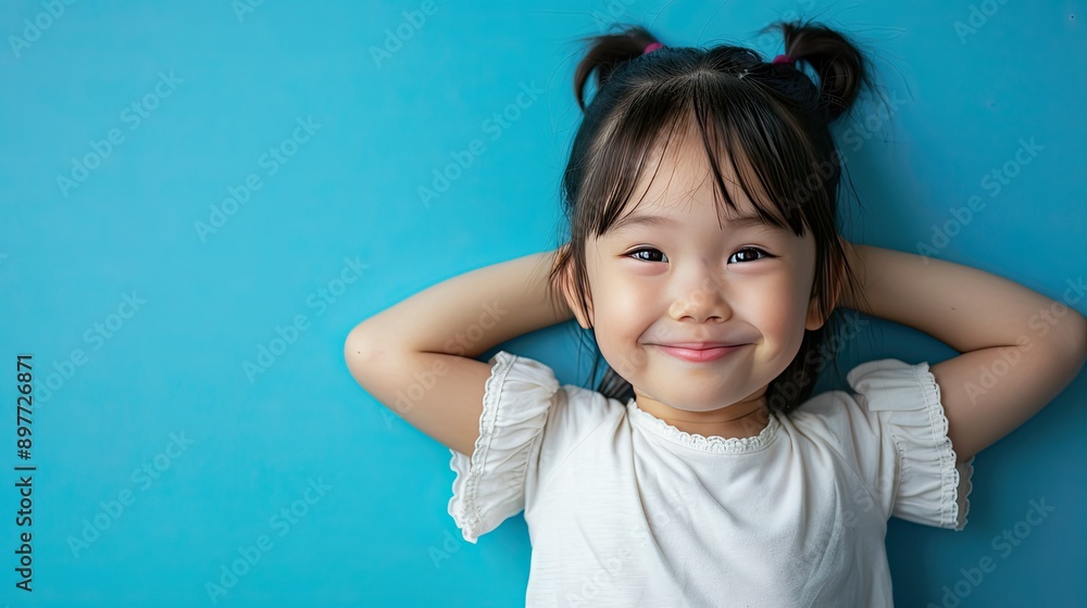Asian child smiling and posing against a bright blue background, showcasing joy and innocence Asian child smiling and posing against a bright blue background, showcasing joy and innocence