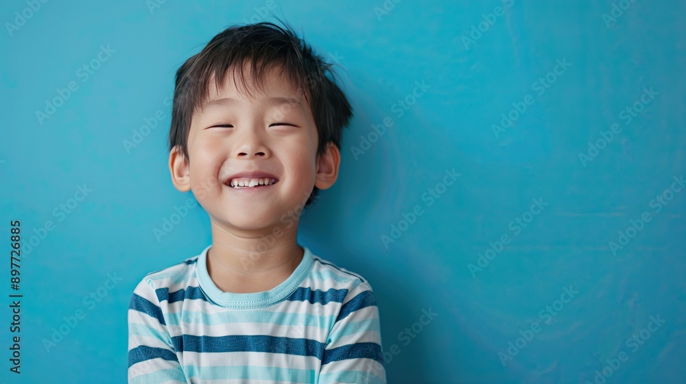 Asian child smiling and posing against a bright blue background, showcasing joy and innocence Asian child smiling and posing against a bright blue background, showcasing joy and innocence