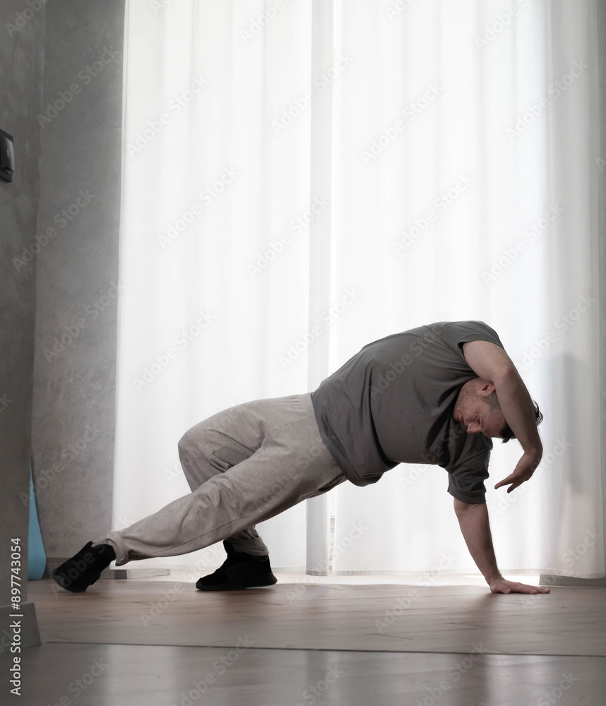 Fototapeta premium Dance in motion, pose of a man in hip-hop style clothes. Sports dancing guy in training poses. Dance training at home.