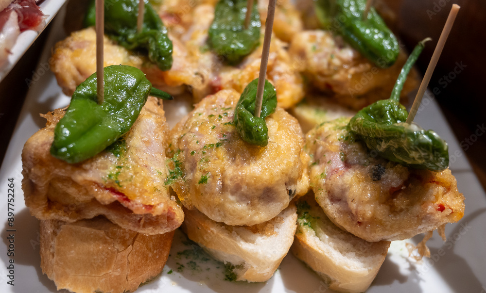 Typical snack of Basque Country, pinchos or pinxtos skewers with small pieces of bread, fish, sea food, sweet green pepper served in bar in San-Sebastian or Bilbao, Spain, close up Typical snack of Basque Country, pinchos or pinxtos skewers with small pieces of bread, fish, sea food, sweet green pepper served in bar in San-Sebastian or Bilbao, Spain, close up