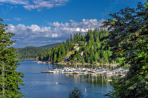 Coastal village and Marina at the Deep Bay in North Vancouver, a bay and yachts in the harbor against the backdrop of a mountain ridge and a blue sky at the spring time