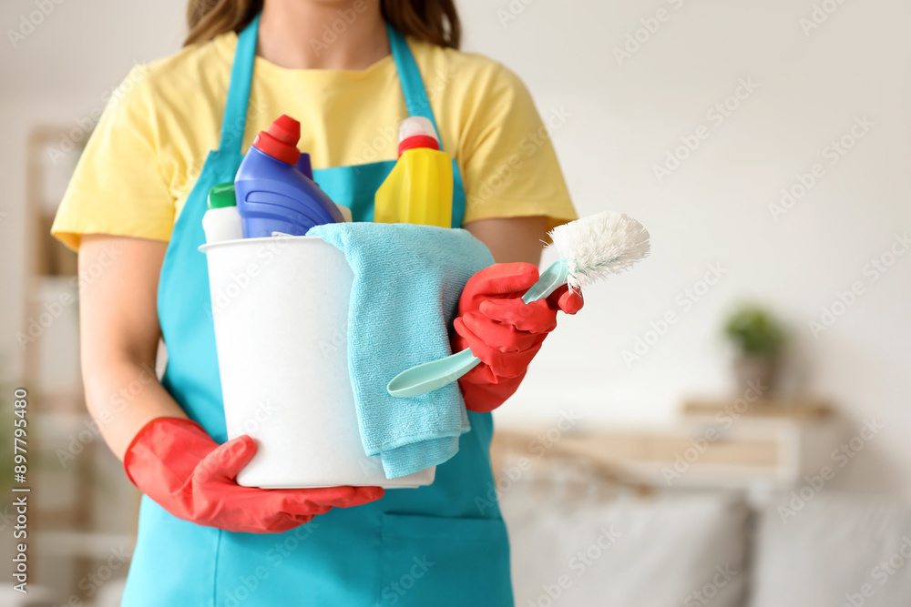 Female janitor with bucket of cleaning supplies in room, closeup Female janitor with bucket of cleaning supplies in room, closeup