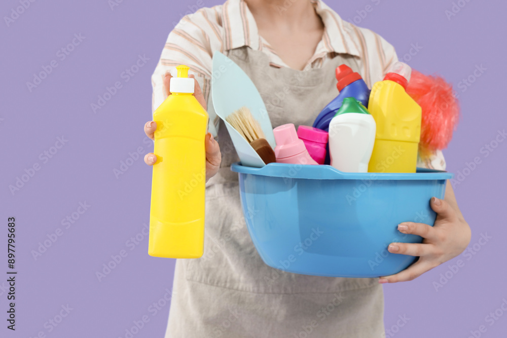 Female janitor with cleaning supplies on lilac background, closeup Female janitor with cleaning supplies on lilac background, closeup