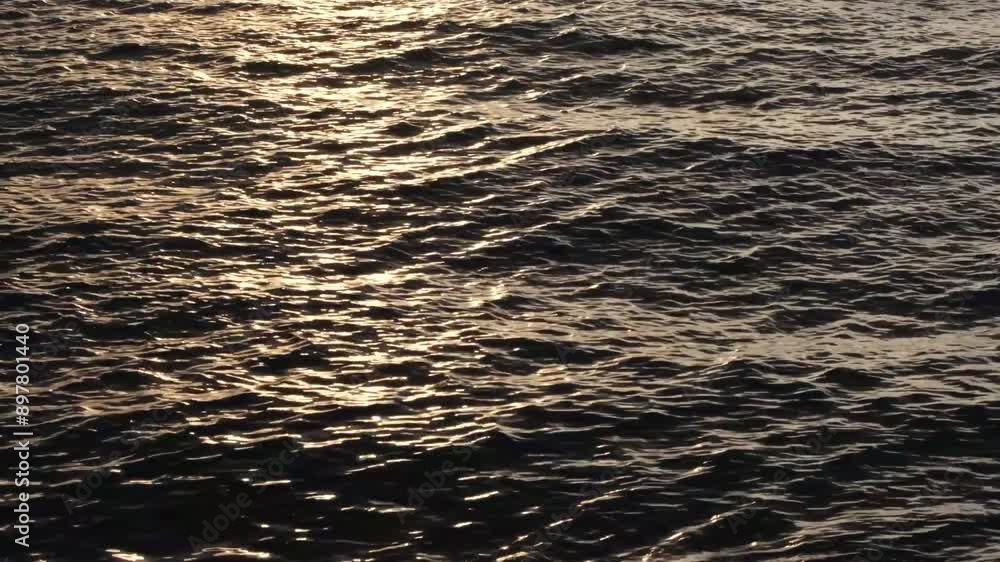 Beautiful yellow or orange sunset reflections on dark blue water surface. Continuously changing wavy sea surface for background. Neutral mirror effect, sun glittering around. Summer, enjoying water. Beautiful yellow or orange sunset reflections on dark blue water surface. Continuously changing wavy sea surface for background. Neutral mirror effect, sun glittering around. Summer, enjoying water.