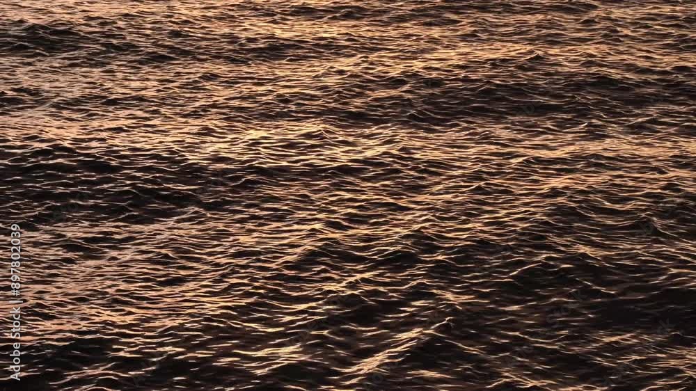Beautiful yellow or orange sunset reflections on dark blue water surface. Continuously changing wavy sea surface for background. Neutral mirror effect, sun glittering around. Summer, enjoying water. Beautiful yellow or orange sunset reflections on dark blue water surface. Continuously changing wavy sea surface for background. Neutral mirror effect, sun glittering around. Summer, enjoying water.