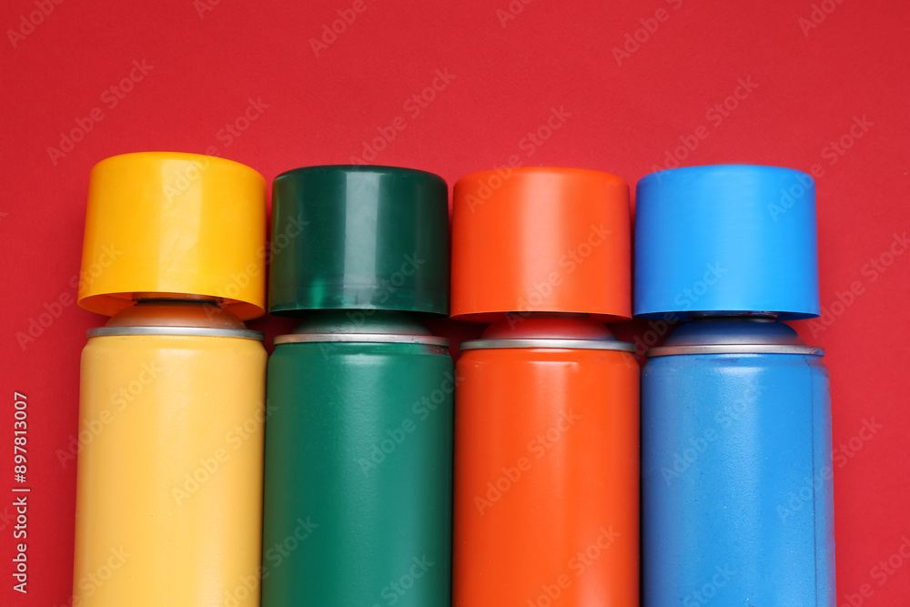 Many spray paint cans on red background, top view Many spray paint cans on red background, top view