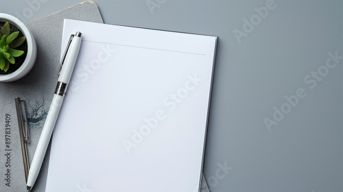 White paper and pen on gray background with space for text top down view of work area.