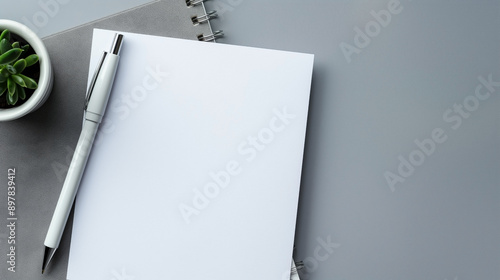White paper and pen on gray background with space for text top down view of work area.