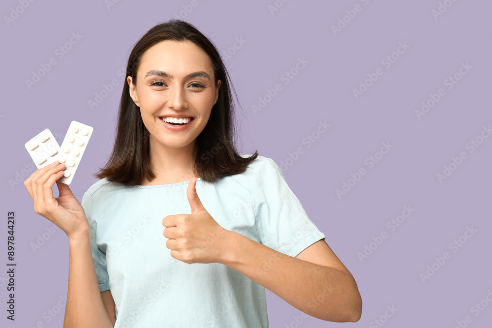 Pretty young woman with pills showing thumb-up on lilac background Pretty young woman with pills showing thumb-up on lilac background