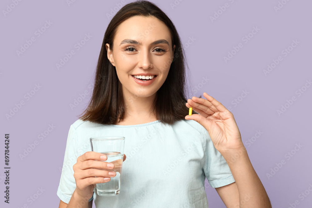 Pretty young woman with glass of water and pill on lilac background Pretty young woman with glass of water and pill on lilac background