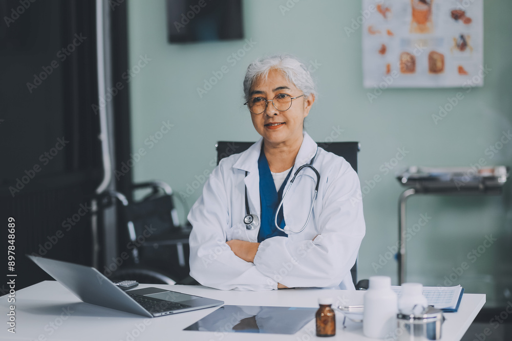 Confident female doctor sitting with laptop at desk in clinic Confident female doctor sitting with laptop at desk in clinic
