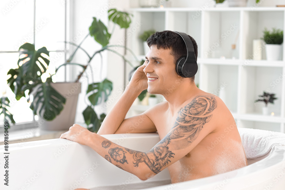 Handsome young man in headphones taking bath at home Handsome young man in headphones taking bath at home