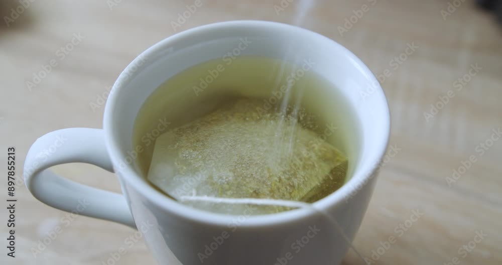 Beautiful close up slow motion shot of a white cup with hot water and chamomile while pouring white sugar from an envelope. Beautiful close up slow motion shot of a white cup with hot water and chamomile while pouring white sugar from an envelope.