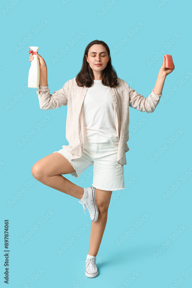 Beautiful young woman with bottle of detergent and sponge meditating on blue background Beautiful young woman with bottle of detergent and sponge meditating on blue background