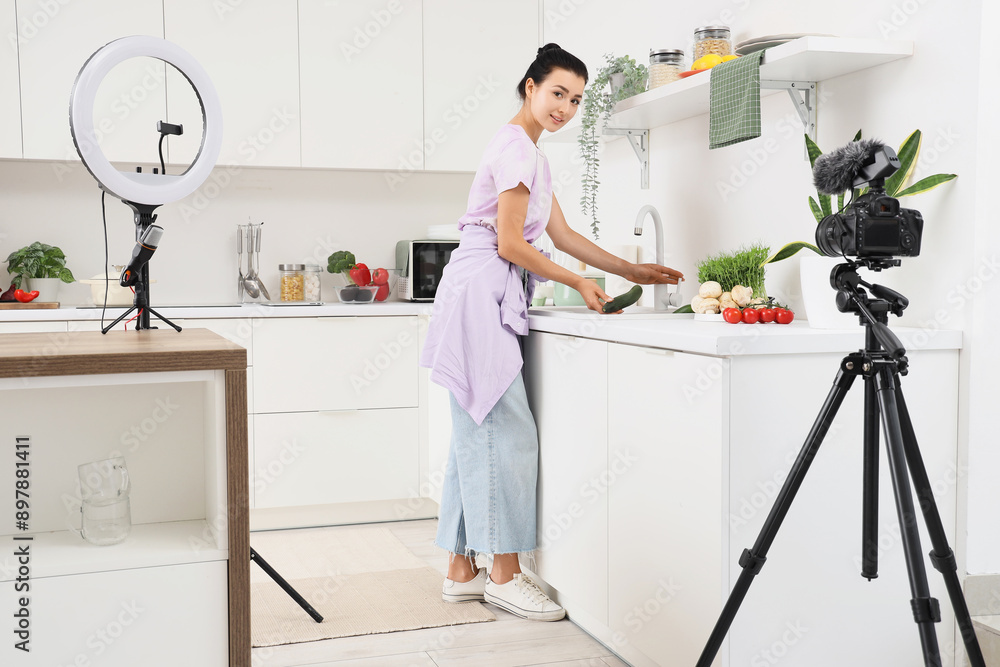 Young woman washing cucumber while recording cooking video class in kitchen Young woman washing cucumber while recording cooking video class in kitchen