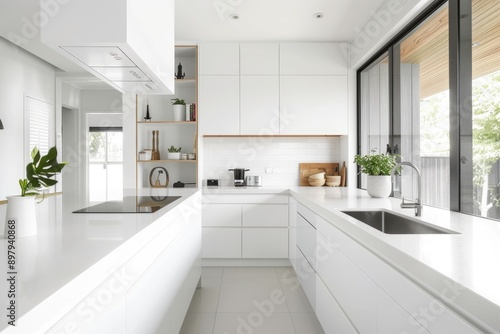 Minimalistic white kitchen featuring white countertops and cabinets, bathed in natural light.