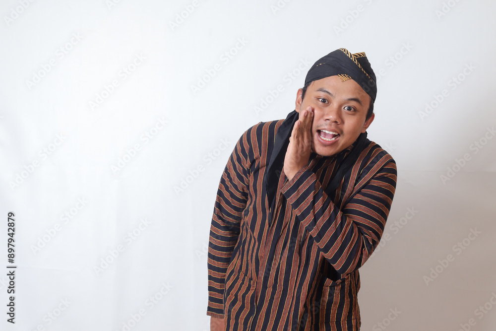 © Yazid Nasuha - Portrait of serious Asian man in javanese cloth with blangkon hat whispering malicious talk conversation, hand on mouth telling secret rumor. Isolated image on white background © Yazid Nasuha - Portrait of serious Asian man in javanese cloth with blangkon hat whispering malicious talk conversation, hand on mouth telling secret rumor. Isolated image on white background