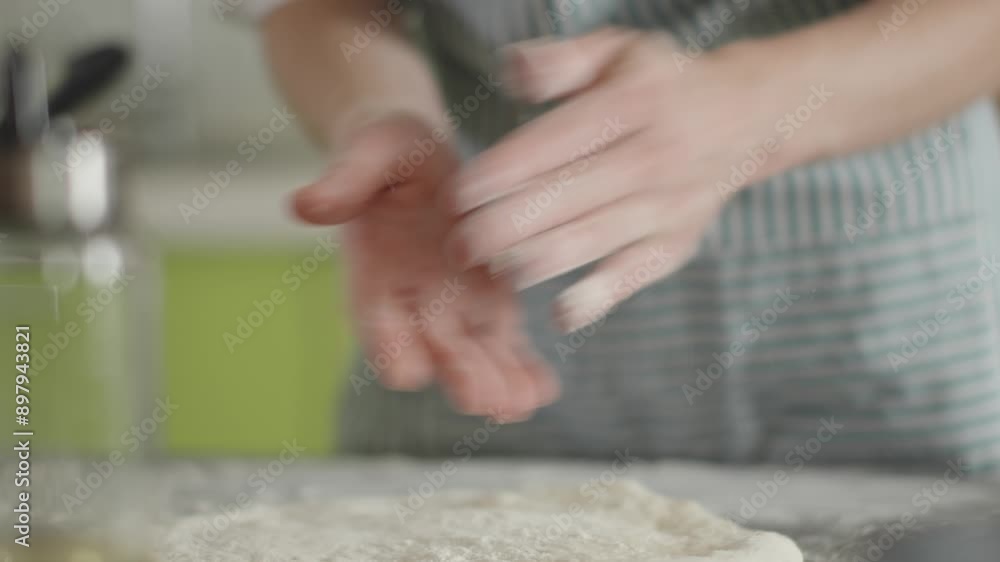 A female chef is kneading dough with her hands in the kitchen for making homemade pizza. A female chef is kneading dough with her hands in the kitchen for making homemade pizza.