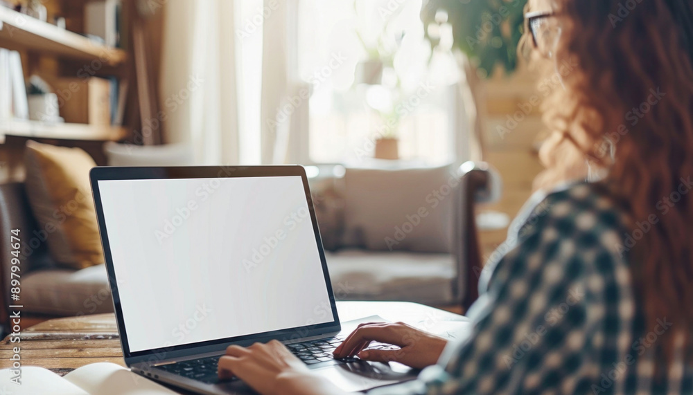 A woman is comfortably seated at a table, working on a laptop computer in a welldesigned room A woman is comfortably seated at a table, working on a laptop computer in a welldesigned room