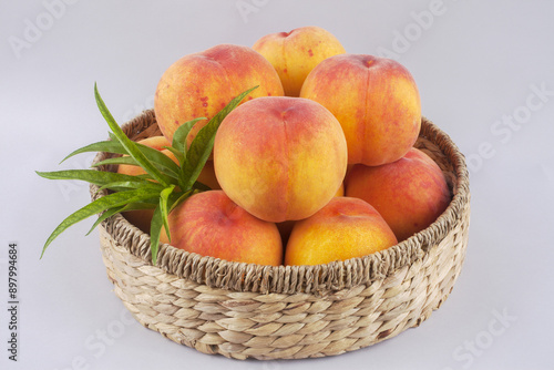 Close-up of yellow peaches with green leaves on a basket, South Korea 