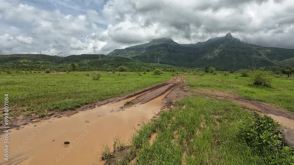 A scenic dirt road winds through lush greenery, leading to panoramic mountain views under a tranquil sky. A scenic dirt road winds through lush greenery, leading to panoramic mountain views under a tranquil sky.