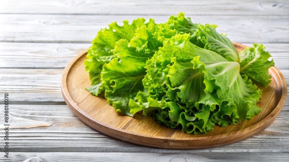 Fresh crisp raw lettuce leaves cut and arranged artfully on a rustic wooden plate on a clean white table, ready for cooking preparation. Fresh crisp raw lettuce leaves cut and arranged artfully on a rustic wooden plate on a clean white table, ready for cooking preparation.