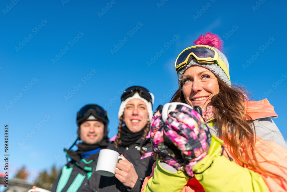 Friends enjoying a winter day on the mountain, sipping tea and embracing the snowy landscape. They are bundled up in warm clothes, laughing and having fun in the crisp mountain air Friends enjoying a winter day on the mountain, sipping tea and embracing the snowy landscape. They are bundled up in warm clothes, laughing and having fun in the crisp mountain air
