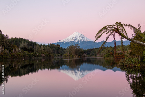 Perfect peaceful dawn reflection of the snow-covered volcanic cone of Mt Taranaki in Lake Mangamahoe on New Zealand’s North Island