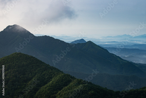 안개가 낀 여러개의 산이 보이는 산 정상에서의 아침.	
 photo