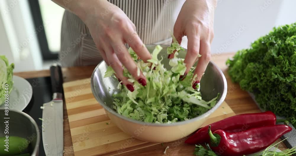 Woman mixes chopped cabbage and cucumbers with hands Woman mixes chopped cabbage and cucumbers with hands