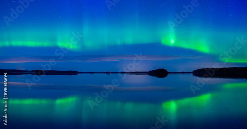 Northern lights dancing over calm lake in Farnebofjarden national park in north of Sweden. photo