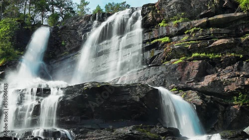 A stunning view of a waterfall plunging over a steep cliff, the water glistening as it flows gracefully amidst the verdant landscape. photo