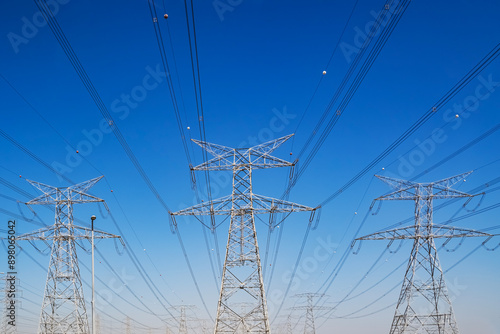 High voltage electrical towers and lines, symmetrical view with blue sky in the background, Dubai, United Arab Emirates.