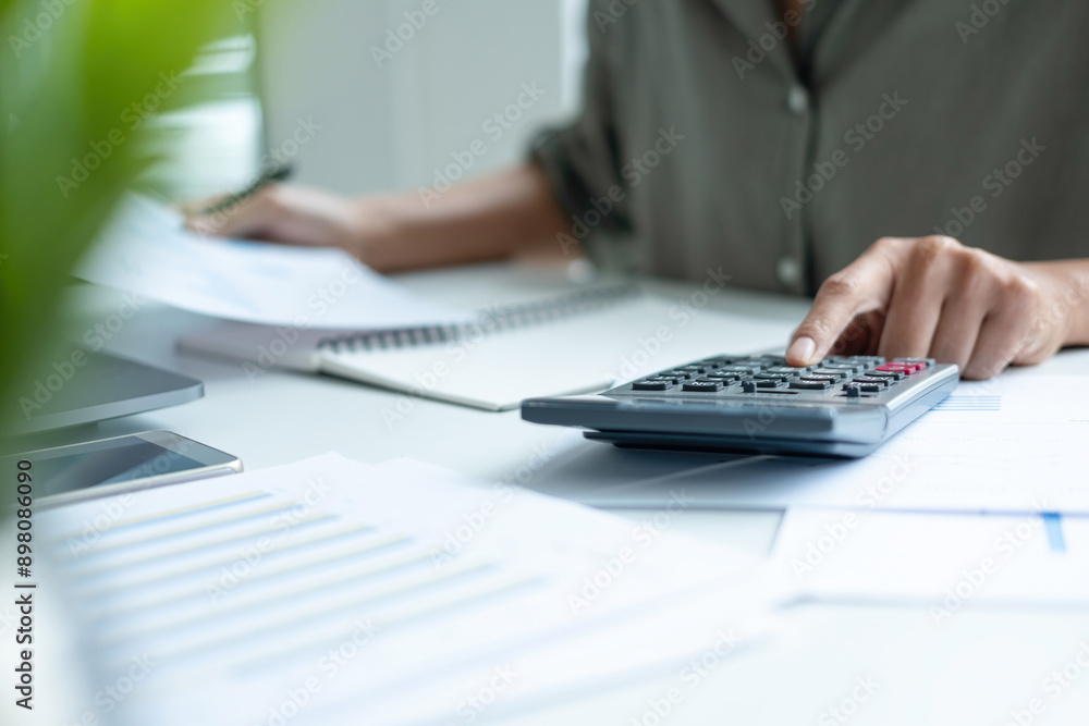 Businesswoman sitting at desk on couch in workplace or at home working on laptop and analyzing data on charts and graphs and writing on papers to make business plan and strategies for company, Businesswoman sitting at desk on couch in workplace or at home working on laptop and analyzing data on charts and graphs and writing on papers to make business plan and strategies for company,