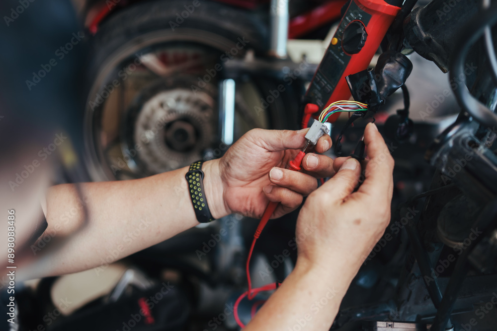 Mechanic repair or wiring motorcycle in garage. Repair or maintenance concept.