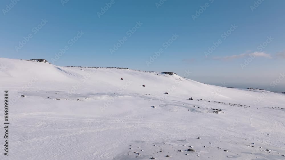 Aerial landscape view of people riding snowmobiles on the icy ground of a glacier in Iceland, on a sunny evening Aerial landscape view of people riding snowmobiles on the icy ground of a glacier in Iceland, on a sunny evening