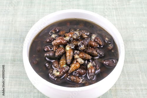 Close-up of Marsh Snails Jangjorim boiled down in soy sauce on white bowl, South Korea 